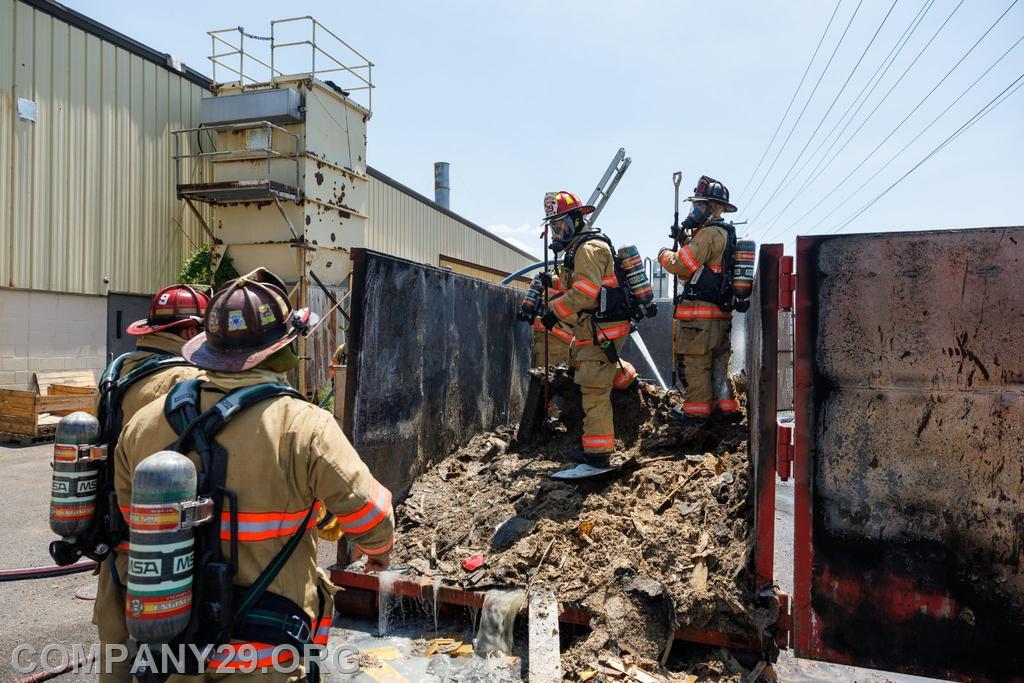 Crews performing overhaul on dumpster fire to reach hot spots